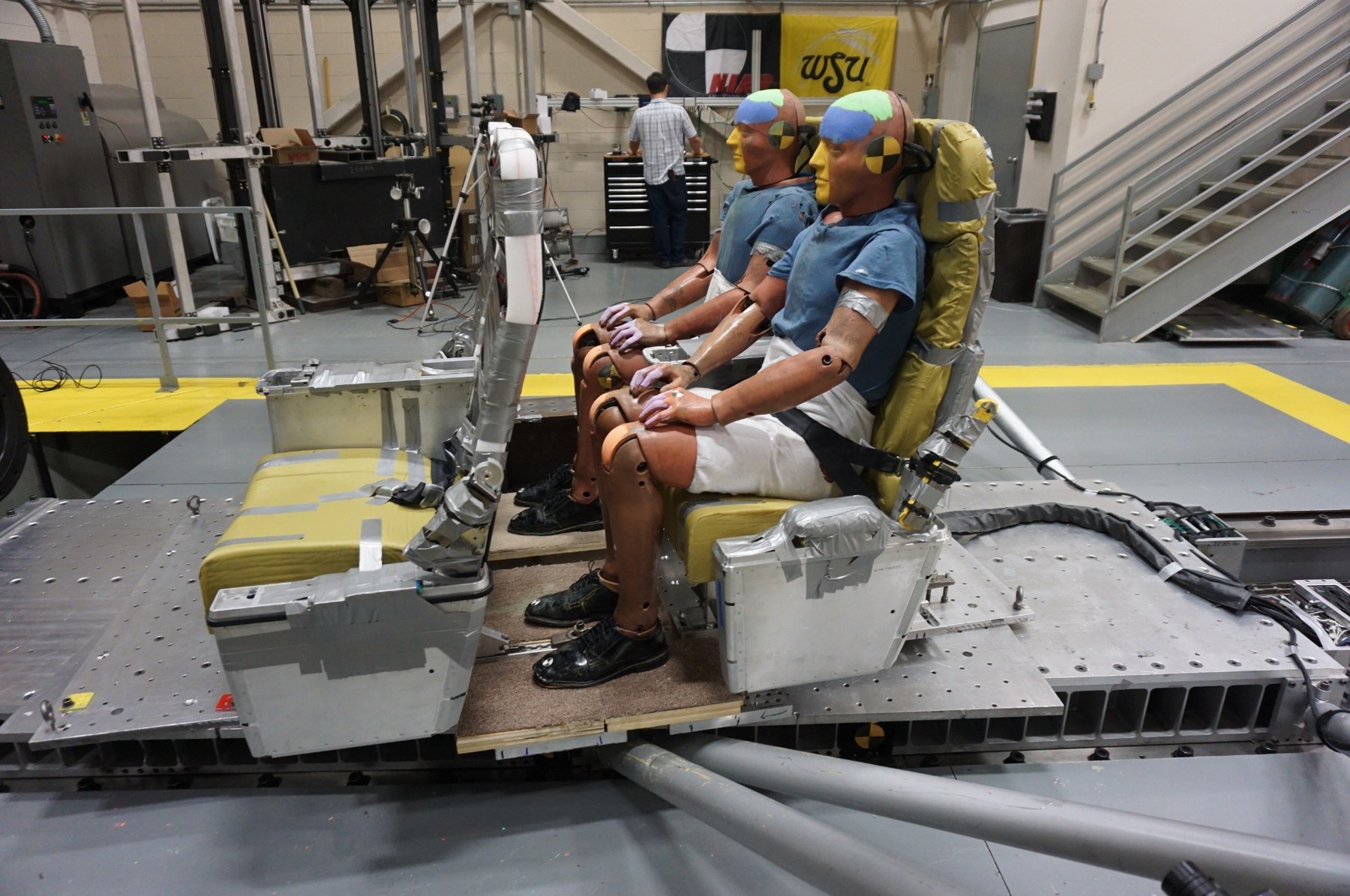 Instrumented crash-test dummies seated in the prepared aircraft-seat test assembly before testing