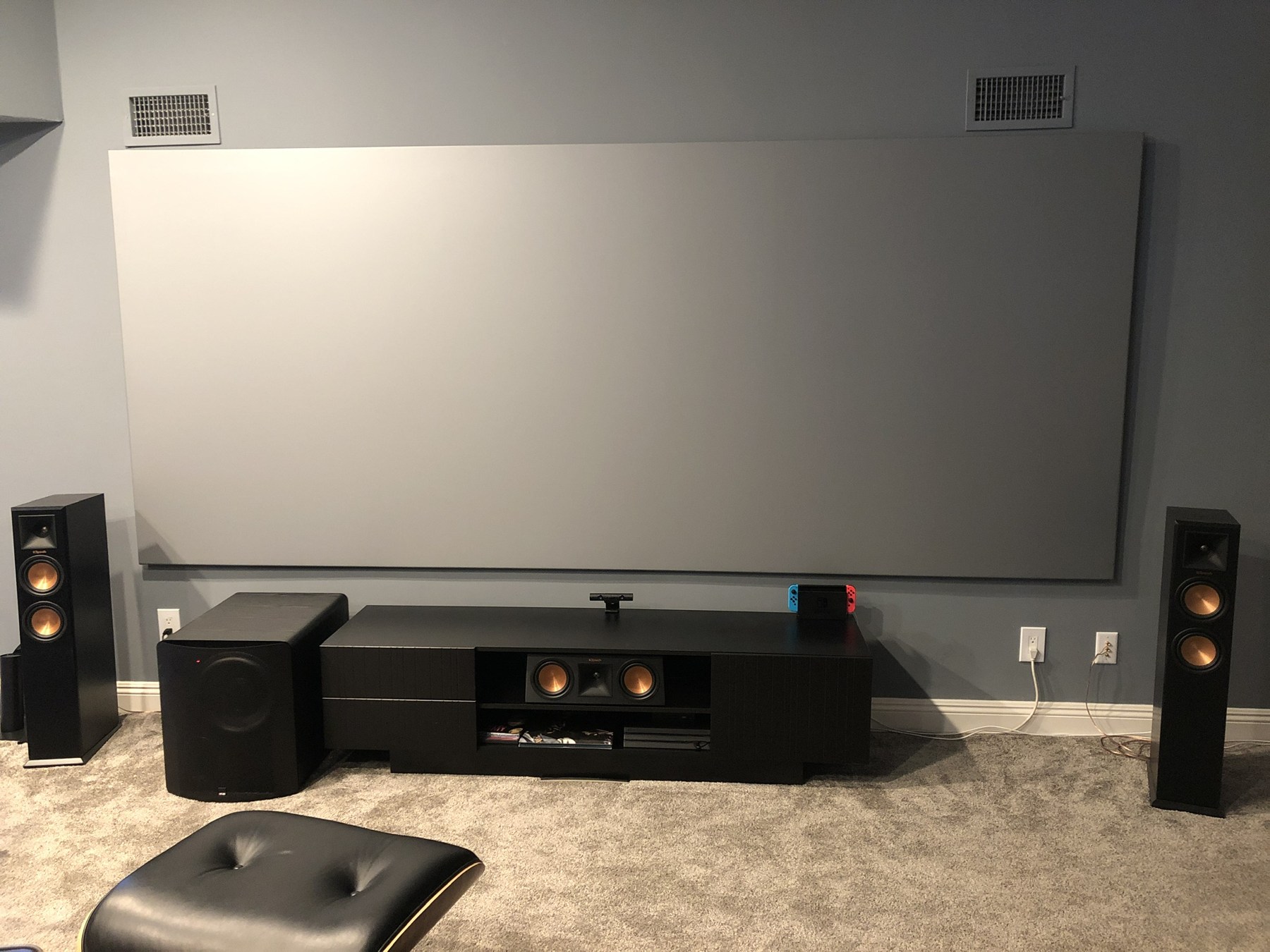 Completed home theater with projection screen, tower speakers, center channel, subwoofer, and media cabinet